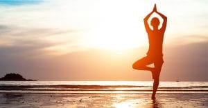 lady in yoga pose on the beach with the sunrise