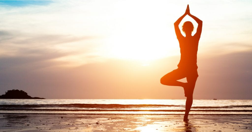 woman on the beach striking a yoga pose