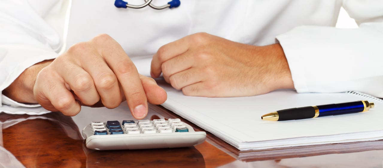 doctor doing his taxes and typing on a calculator