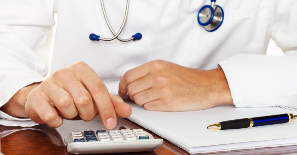 doctor doing his taxes and typing on a calculator