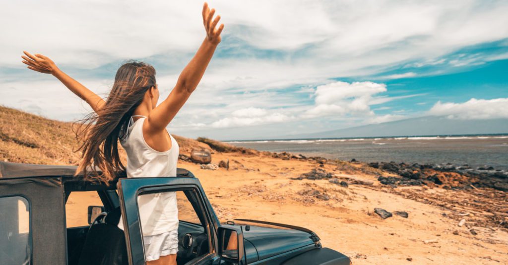 woman standing up in jeep with outstretched arms